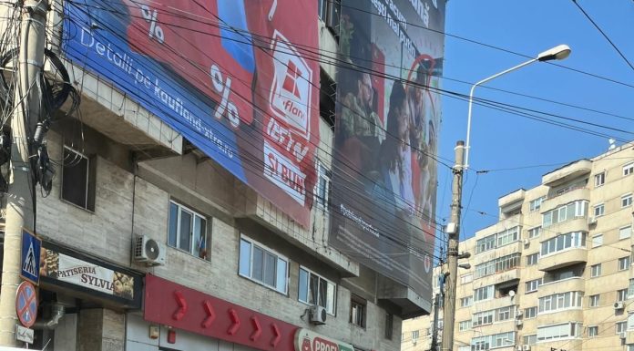 Mesh publicitar desprins de pe faţada unui bloc din Timişoara, cu tot cu plăcile de beton care au cedat, ajungând pe trotuar / Fritz: Cineva a dat găuri / Cineva putea fi acolo în acel moment / Firma mai fusese amendată – FOTO